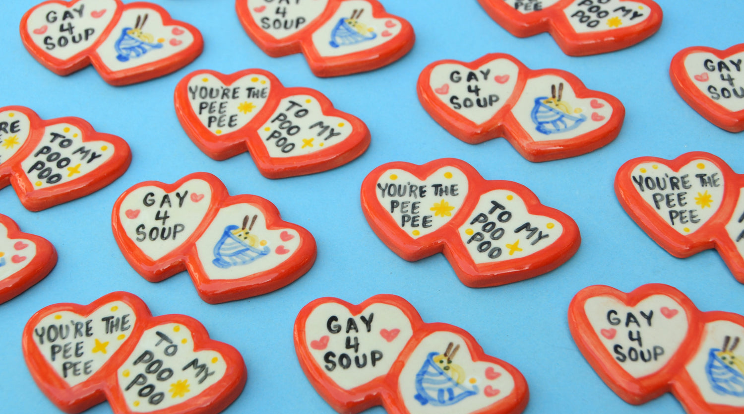 ceramic double red heart shaped magnets in repeating pattern. some say "gay for soup" the rest say "youre the peepee to my poopoo" 