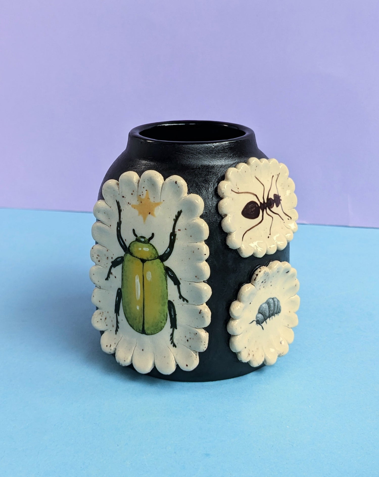 Black ceframic vase with white scalloped 3D design. Decorated with bug illustrations 